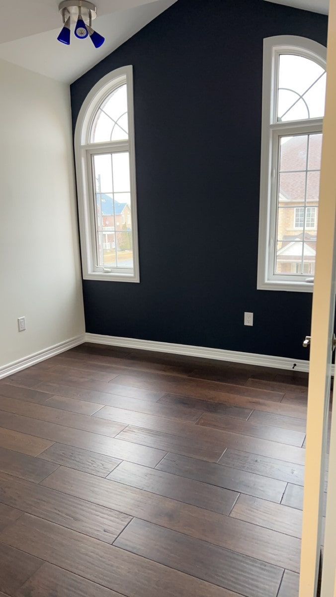 An empty room with a vaulted ceiling and two windows.
