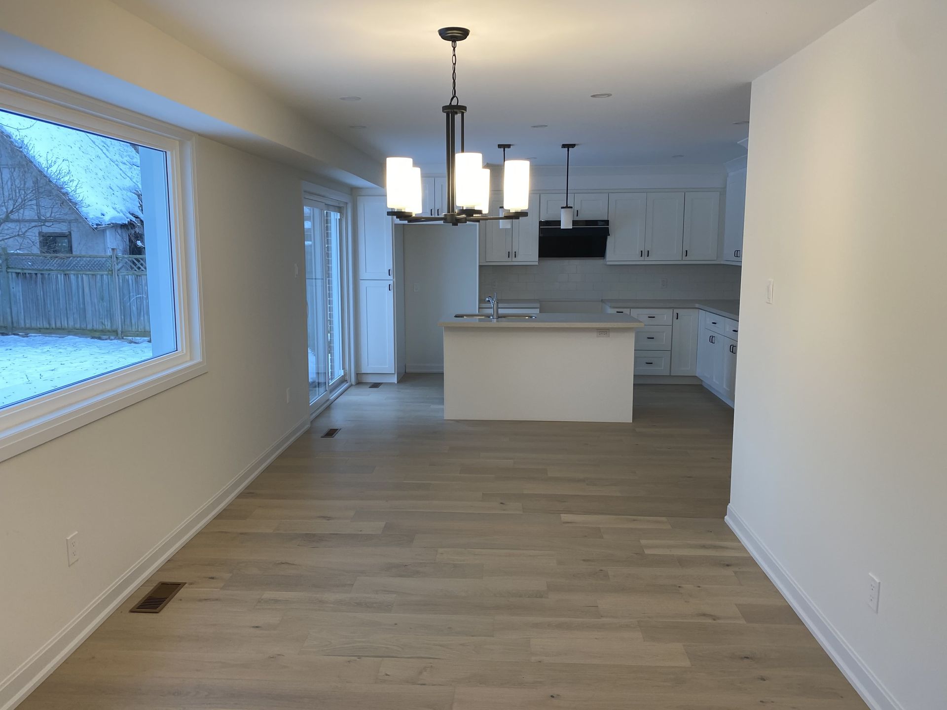 An empty kitchen with a chandelier hanging from the ceiling