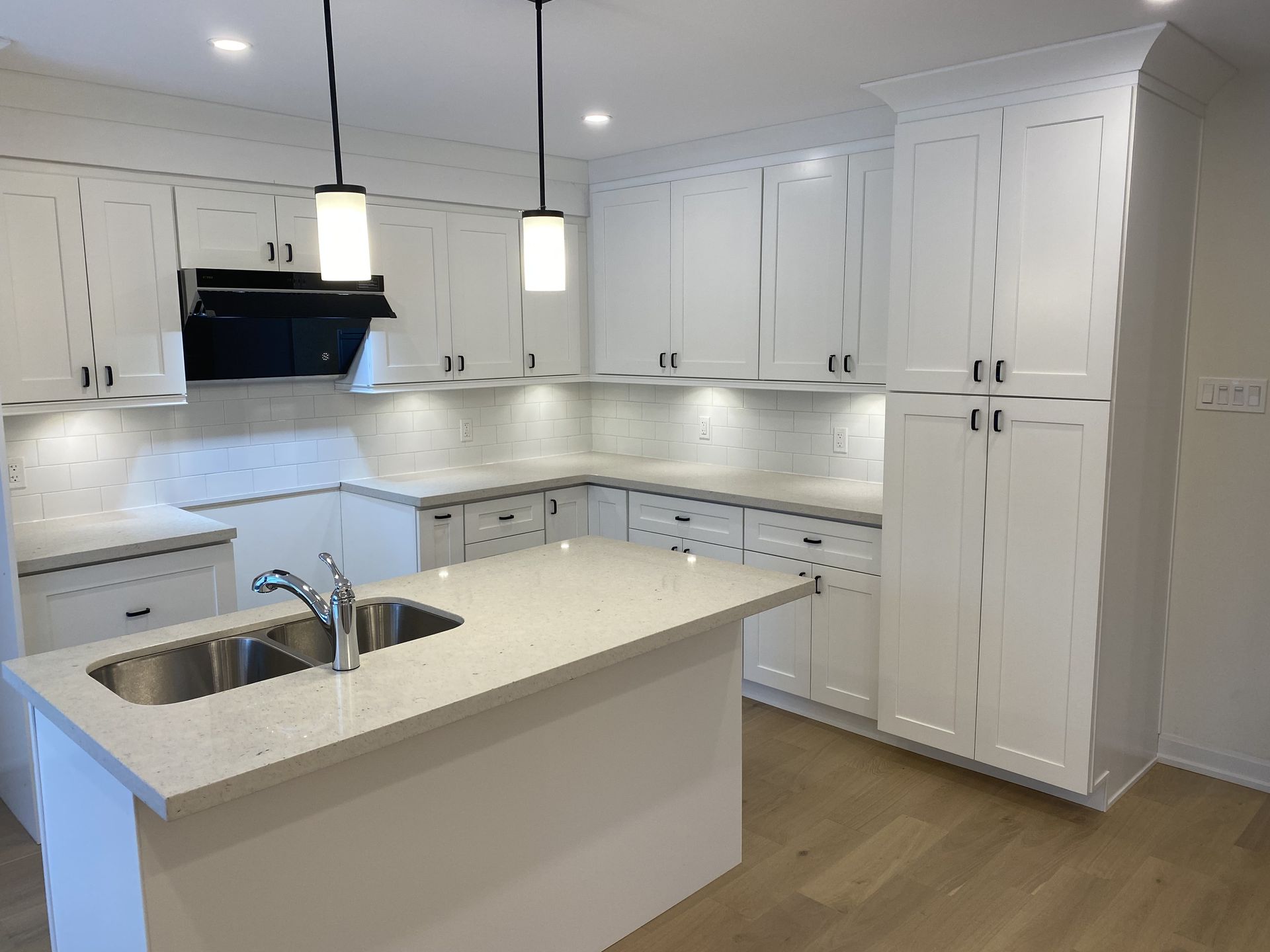 A kitchen with white cabinets , a sink , and a stove.