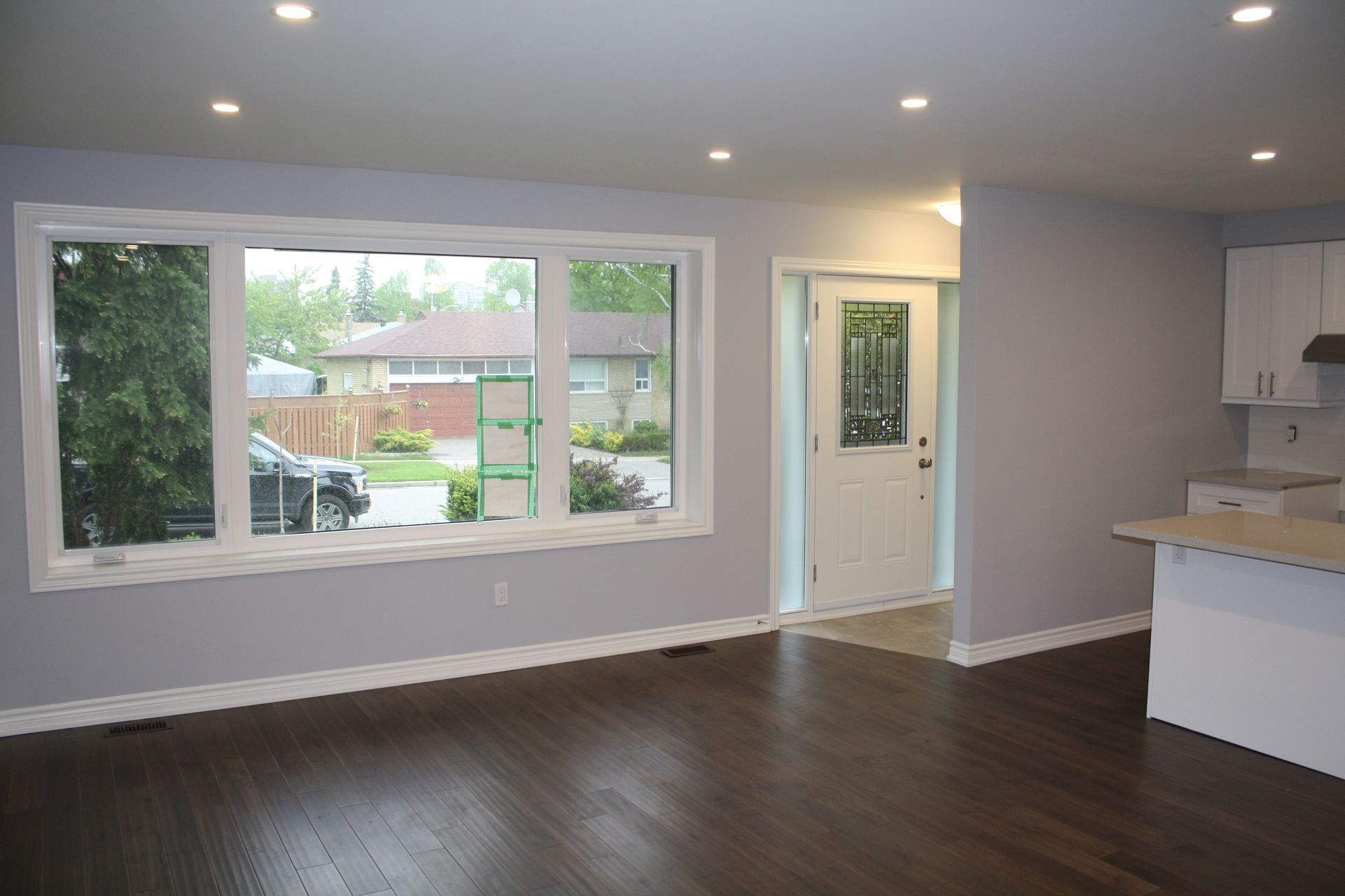 An empty living room with hardwood floors and a large window.