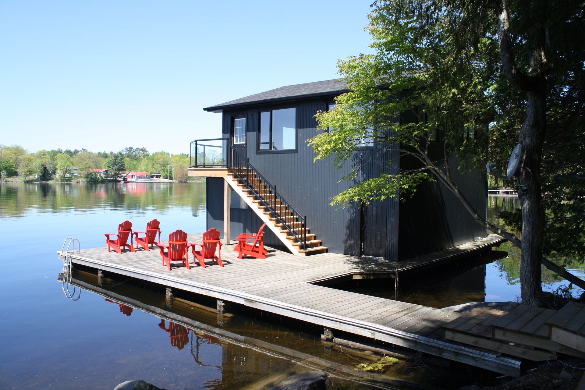 A dock with red chairs and a house in the background