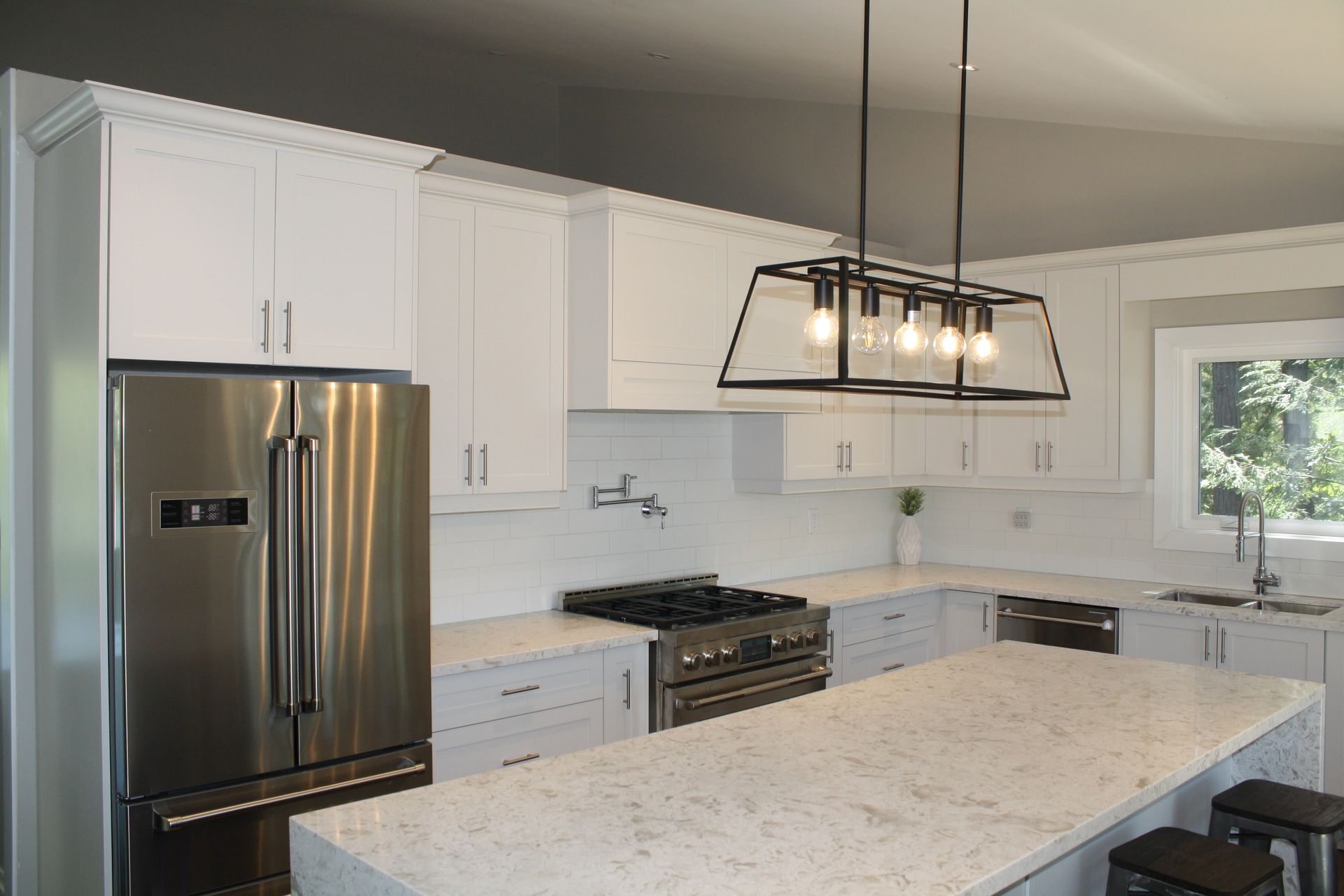A kitchen with white cabinets , stainless steel appliances and a large island.