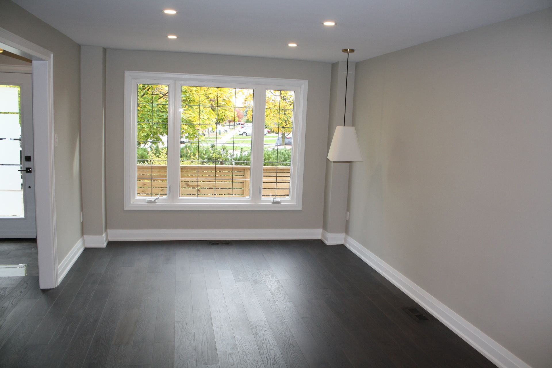 An empty living room with a large window and a lamp