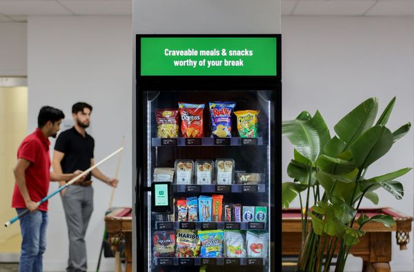 Two men are standing in front of a vending machine.