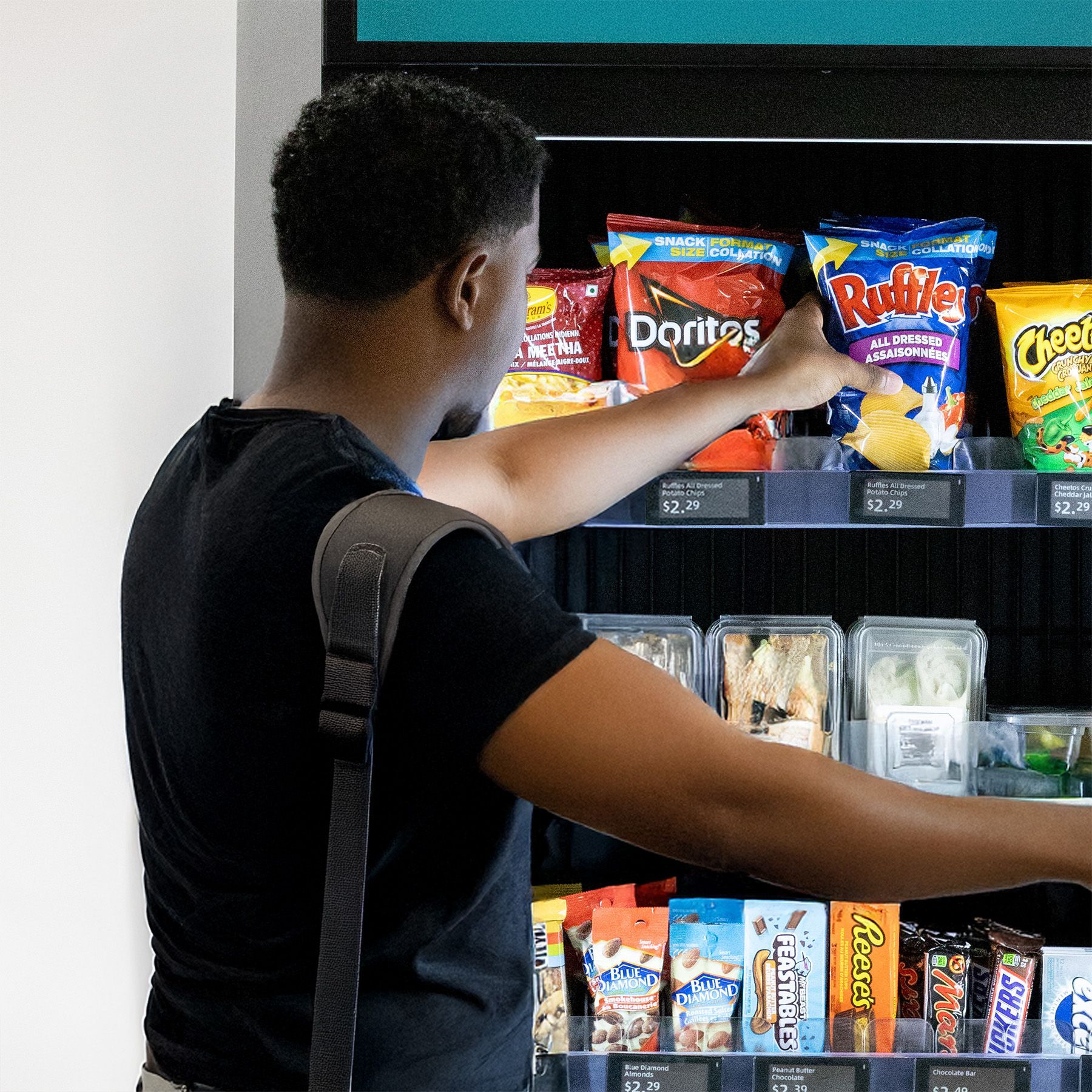 A man is taking a doritos bag out of a vending machine