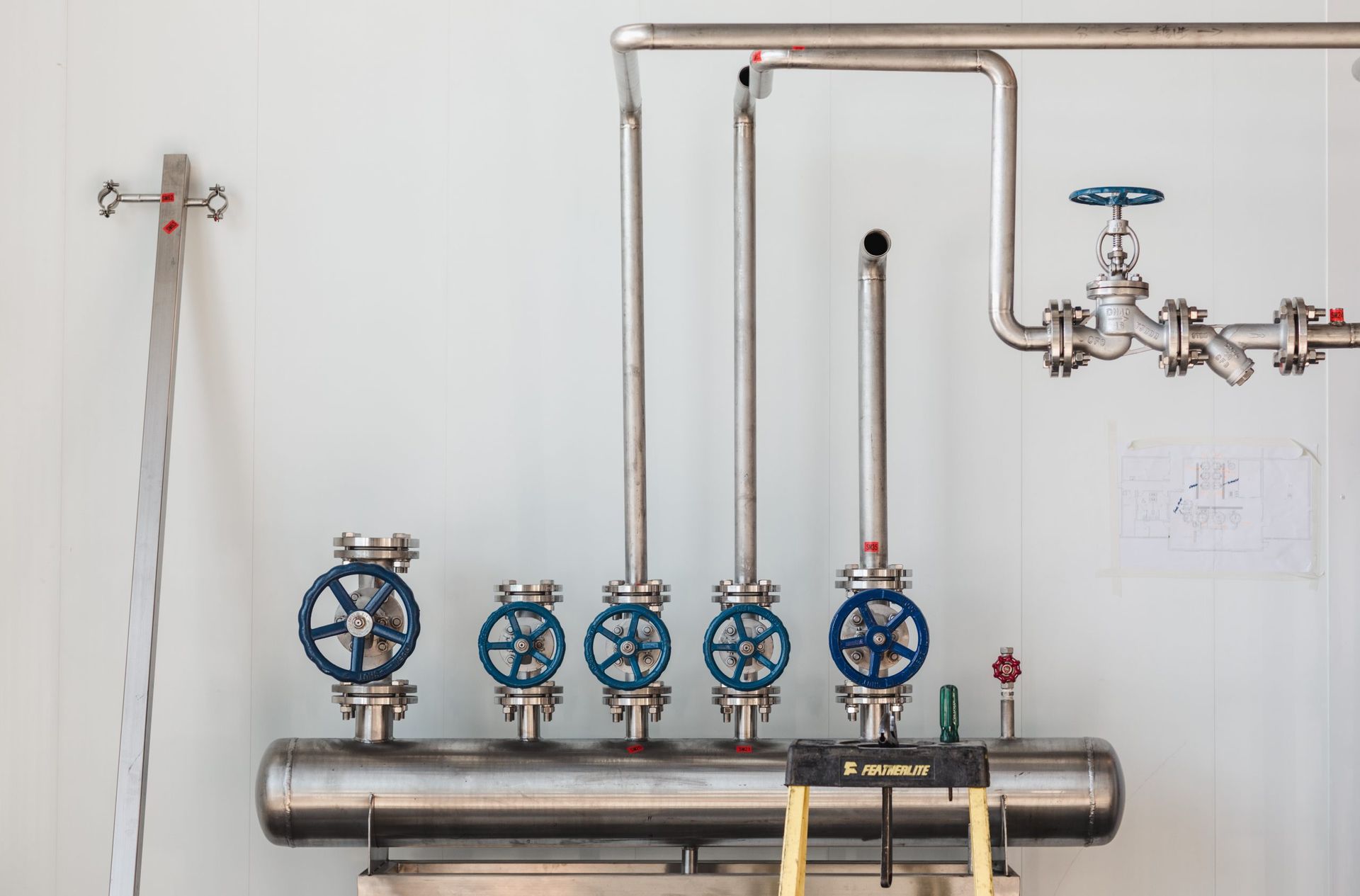 Une rangée de tuyaux en acier inoxydable avec des vannes bleues attachées à eux.