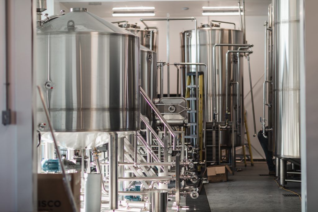 Un entrepôt rempli de nombreux réservoirs en acier inoxydable.