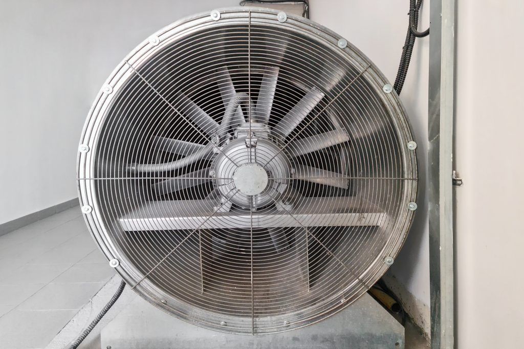 Un grand ventilateur est accroché au mur d'une pièce.