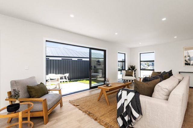 A living room with a couch , chairs , coffee table and sliding glass doors.