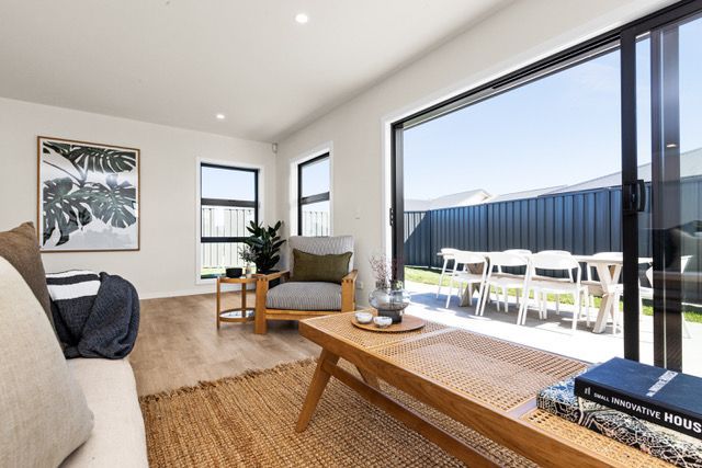 A living room with a couch , chair , coffee table and sliding glass doors leading to a patio.