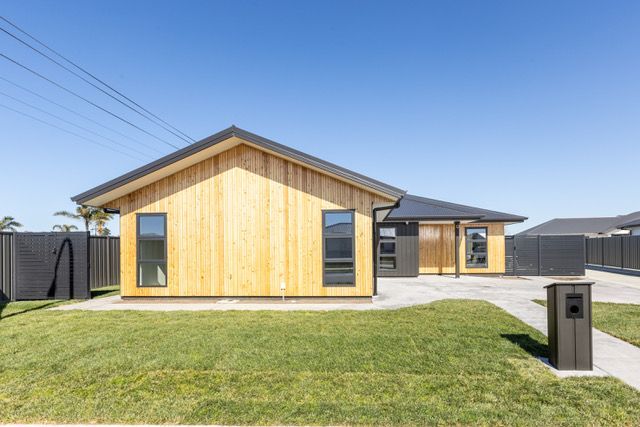 A house with a wooden siding and a black roof is sitting on top of a lush green lawn.