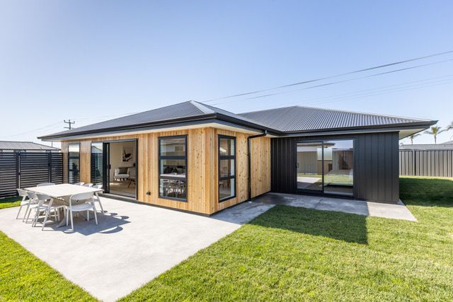 A house with a patio and a table and chairs in front of it.