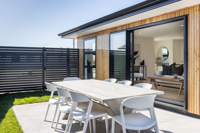 A patio with a table and chairs in front of a house.