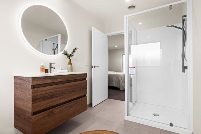 A bathroom with a sink , mirror and shower.