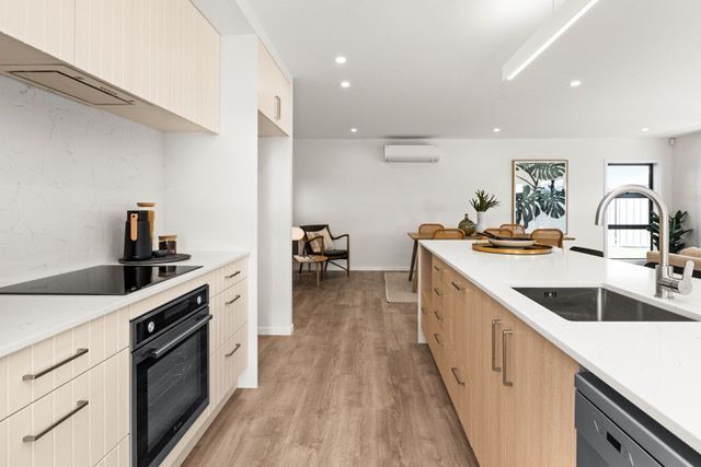 A kitchen with wooden cabinets , a stove top oven , a sink , and a dishwasher.