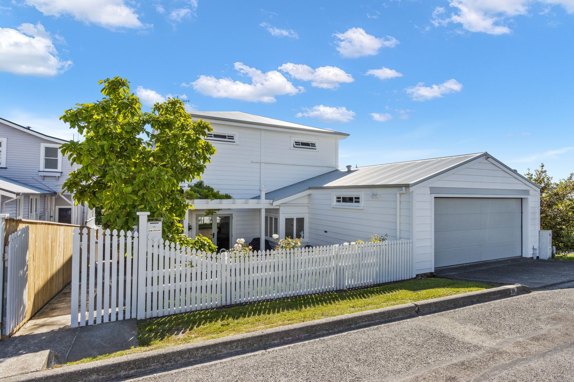 A white house with a white picket fence and a garage.