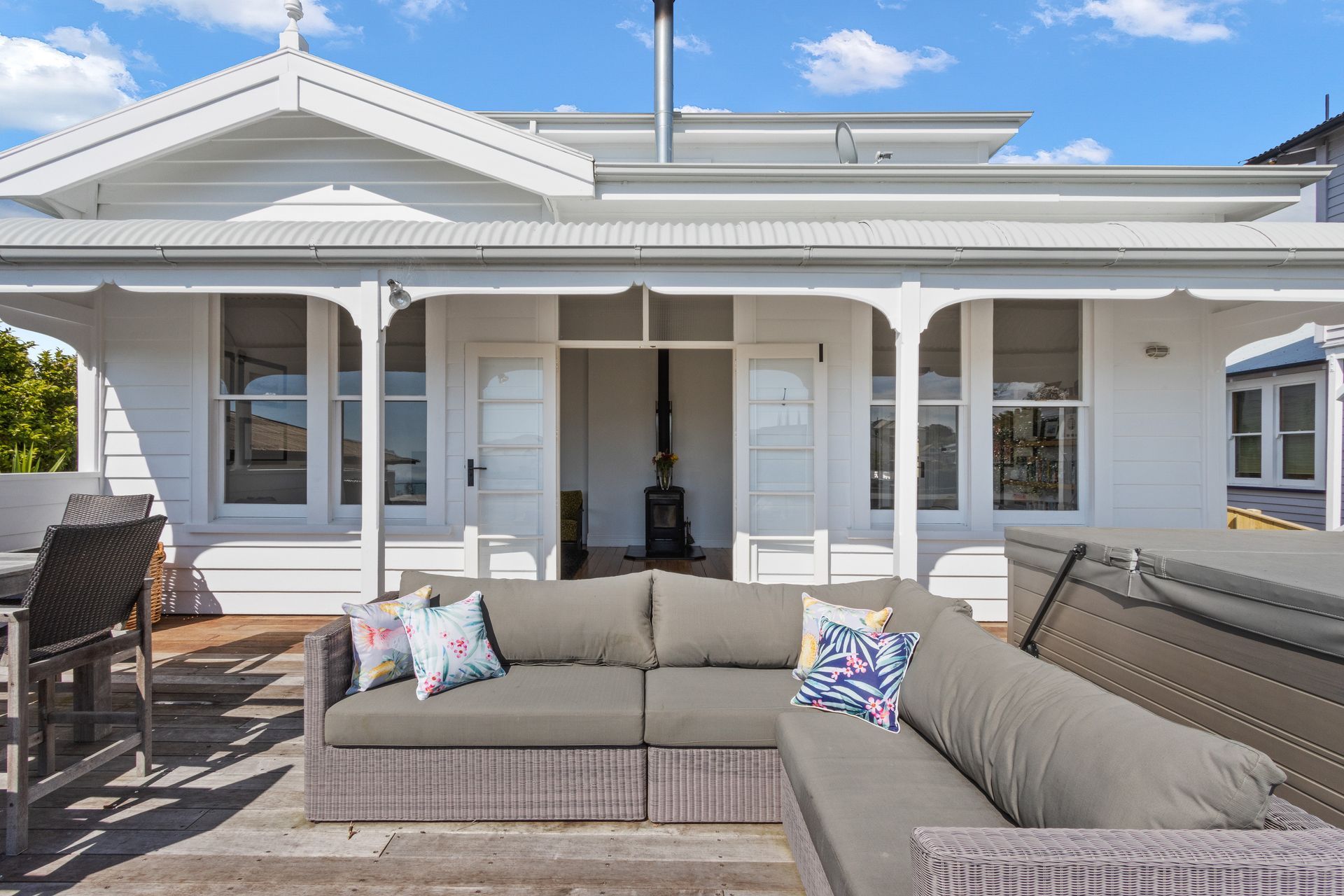 There is a couch on the porch of a white house.