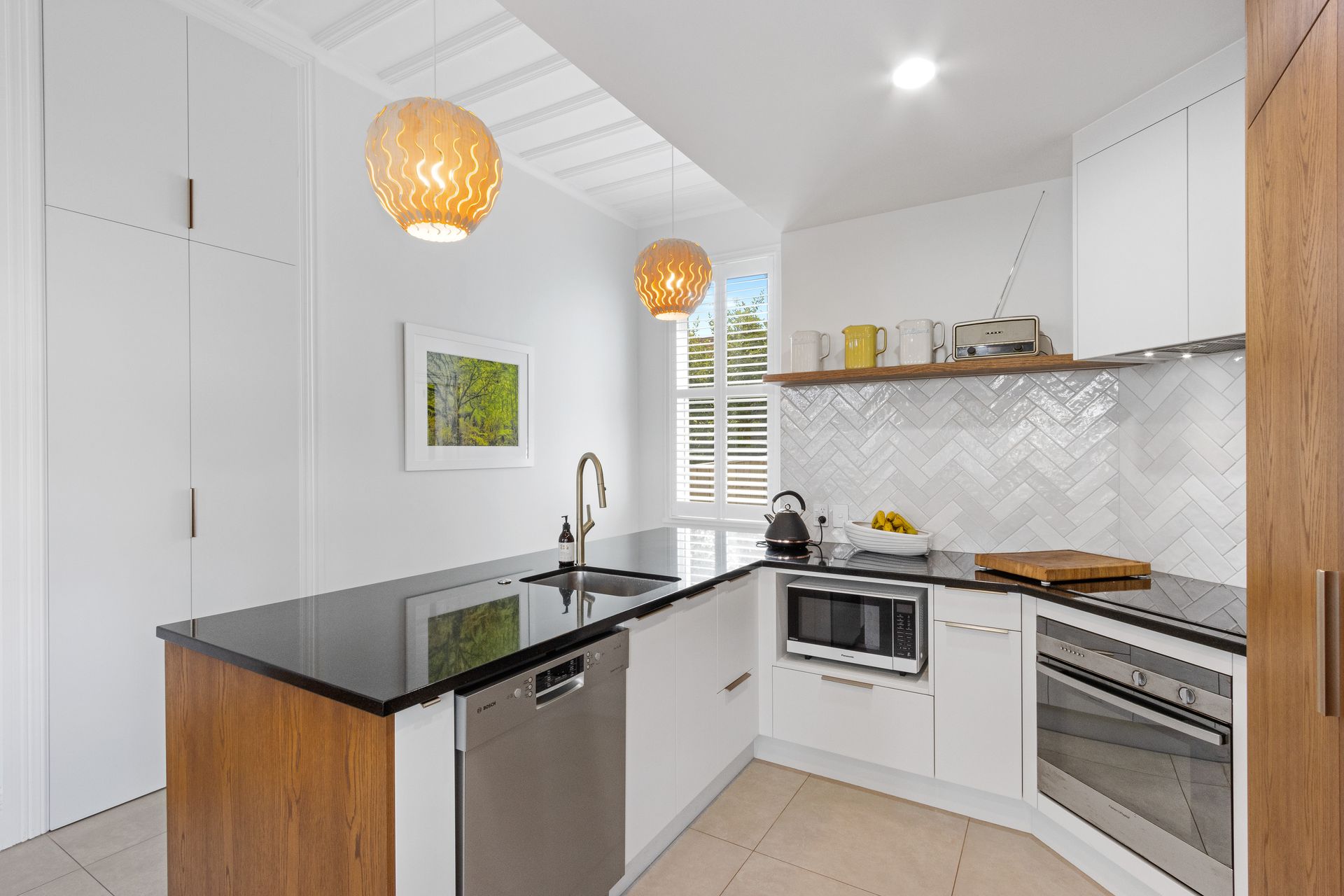 A kitchen with white cabinets , black counter tops , and stainless steel appliances.