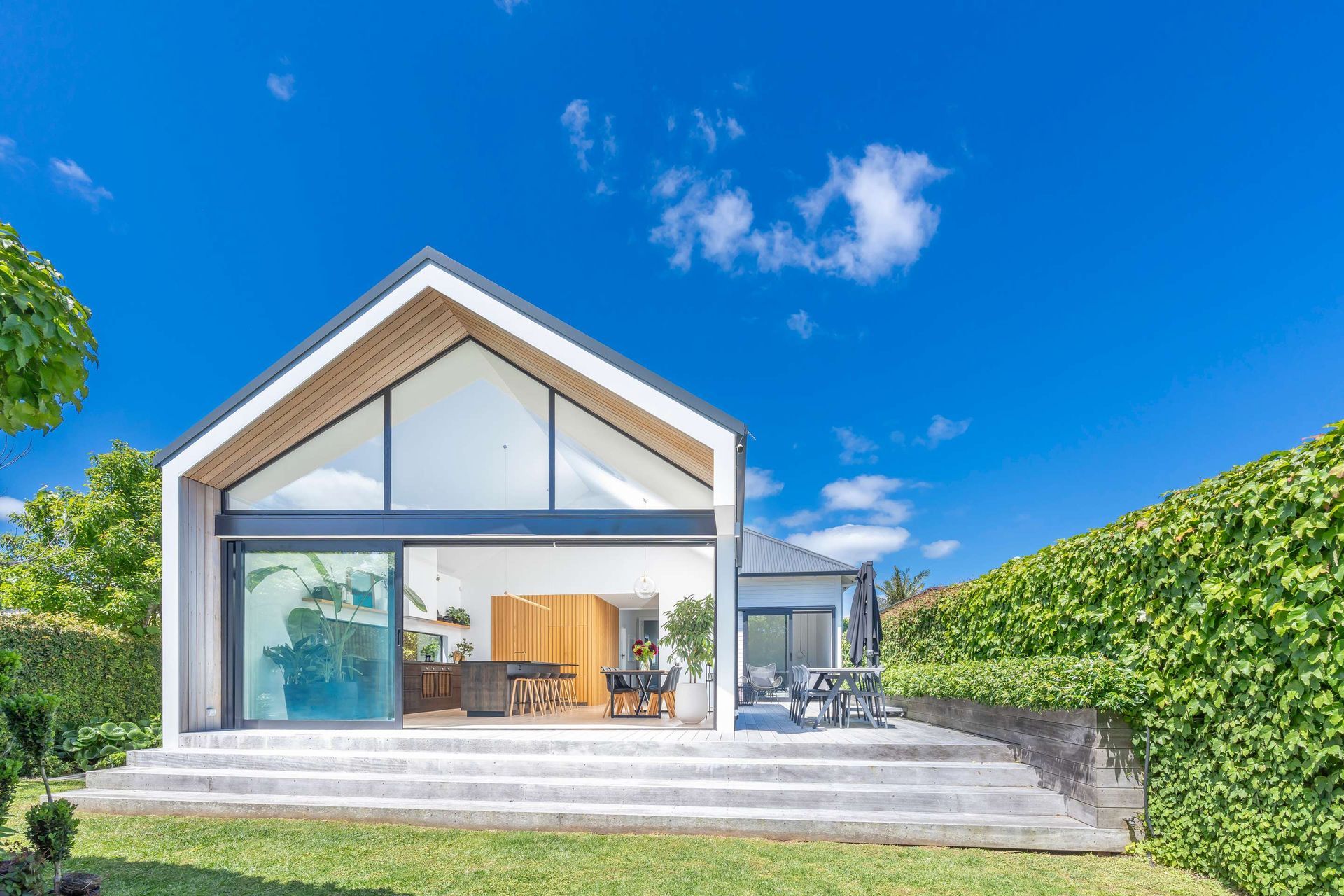 A modern house with a roof that looks like a barn is sitting on top of a lush green lawn.