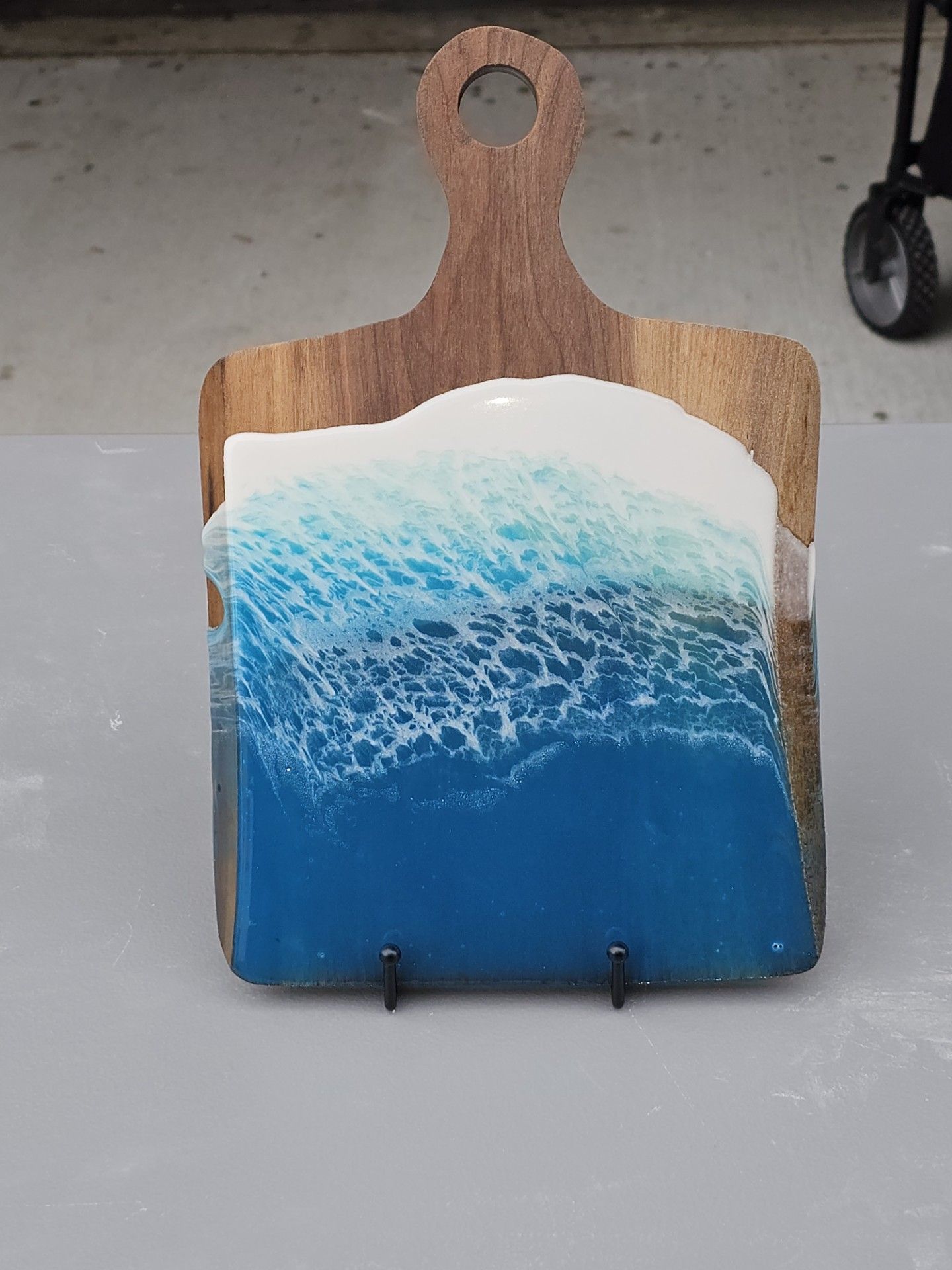 A wooden cutting board with a painting of the ocean on it.