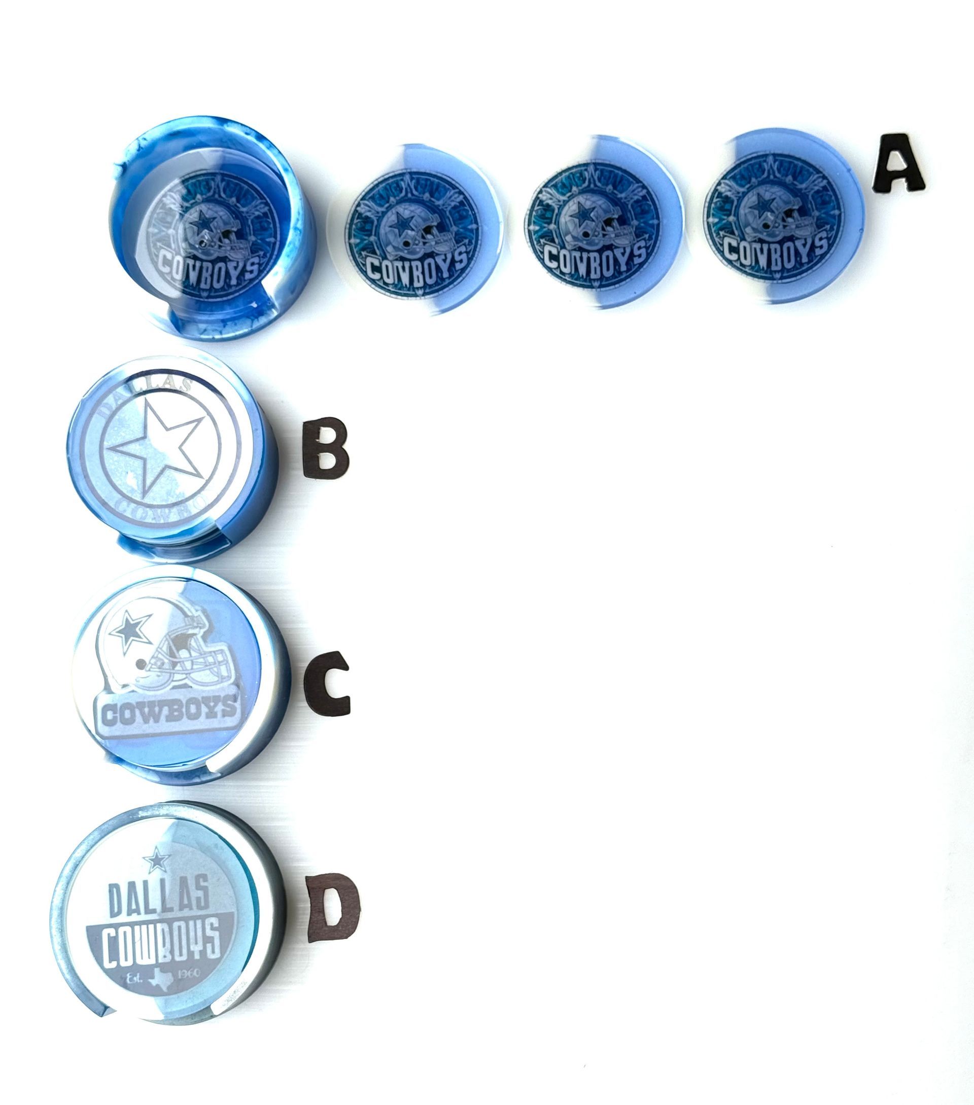 A group of dallas cowboys buttons are lined up on a white surface.