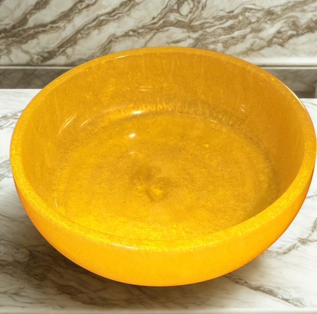 A yellow bowl is sitting on a marble counter top