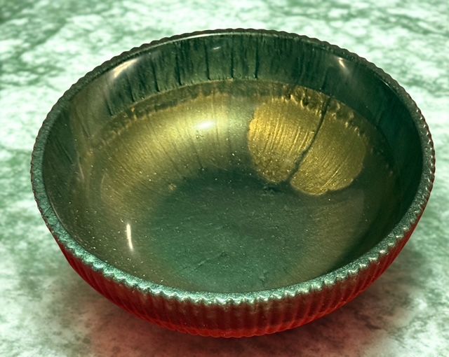 A metal bowl with a red rim is filled with liquid