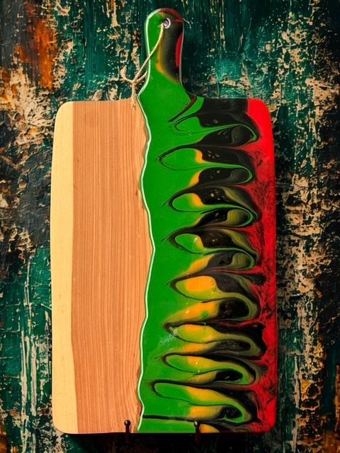 A wooden cutting board with green yellow and red paint on it