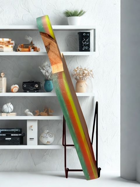 A multi-colored artwork in a stand in front of a white shelf with decorative items.