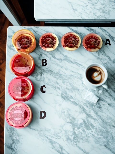 Marble surface with coffee and four coasters: A, B, C, D; mostly red, yellow colors.