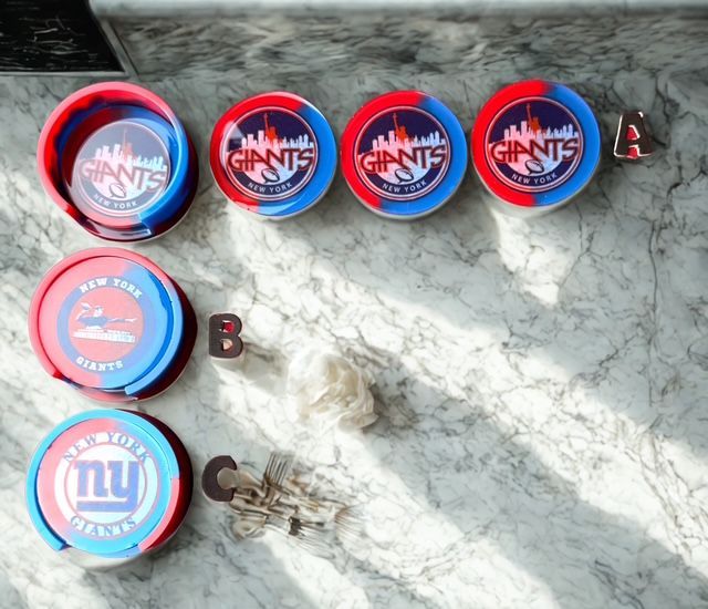 Four New York Giants coasters and a small dish on a marble surface. The coasters are red, white, and blue.