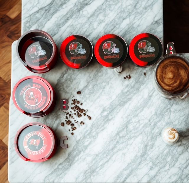 Tampa Bay Buccaneers coasters with coffee and beans on a marble surface.