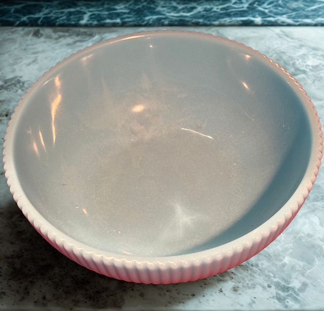 A white bowl with a pink rim sits on a counter