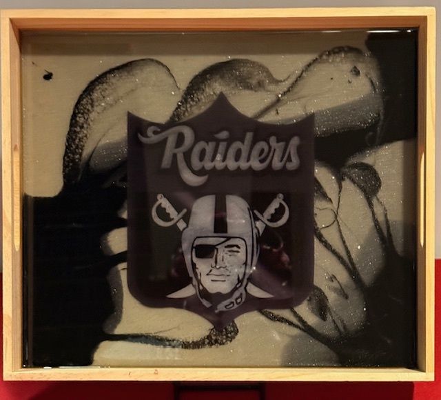 A picture of a raiders logo in a wooden frame