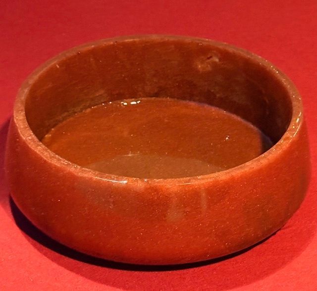 A brown bowl is sitting on a red surface