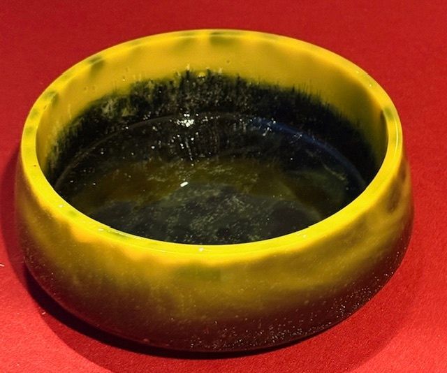 A yellow bowl with a black rim sits on a red surface