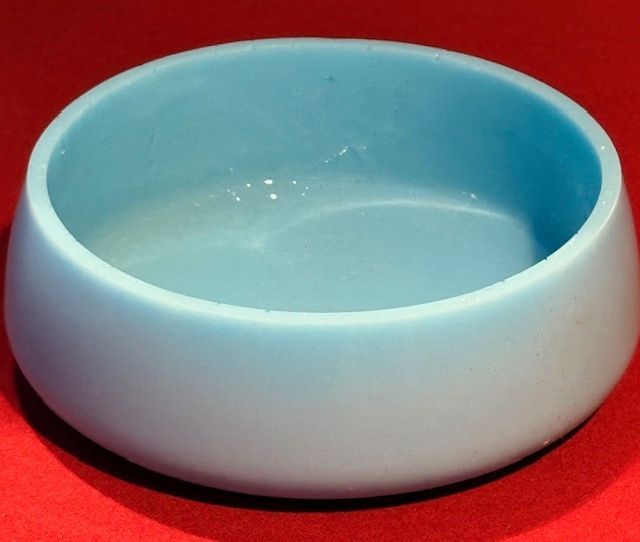 A light blue bowl is sitting on a red surface