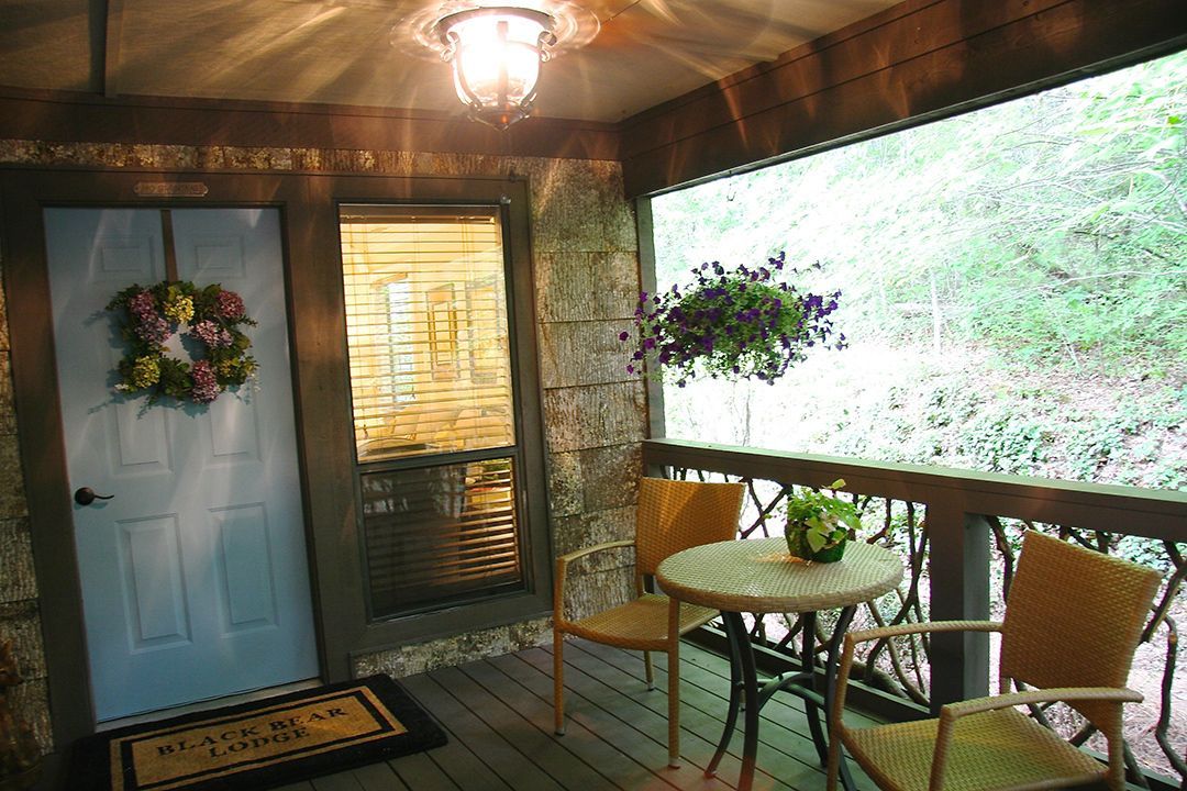 A screened in porch with a table and chairs and a wreath on the door.