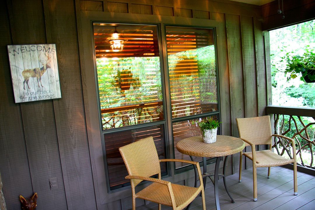 There is a table and chairs on the porch of a house.