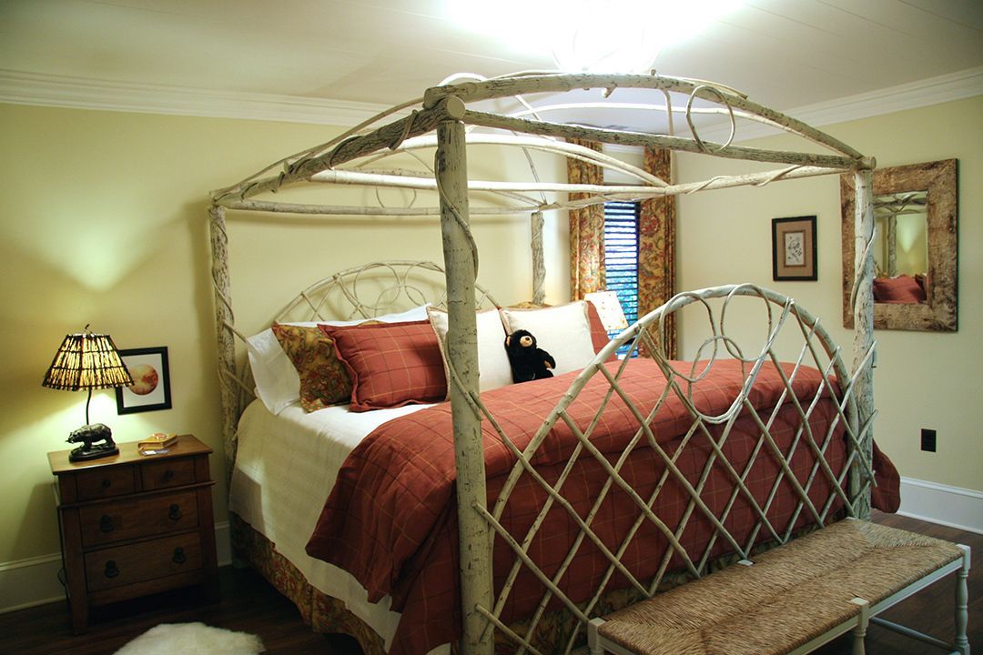 A bedroom with a canopy bed and a bench