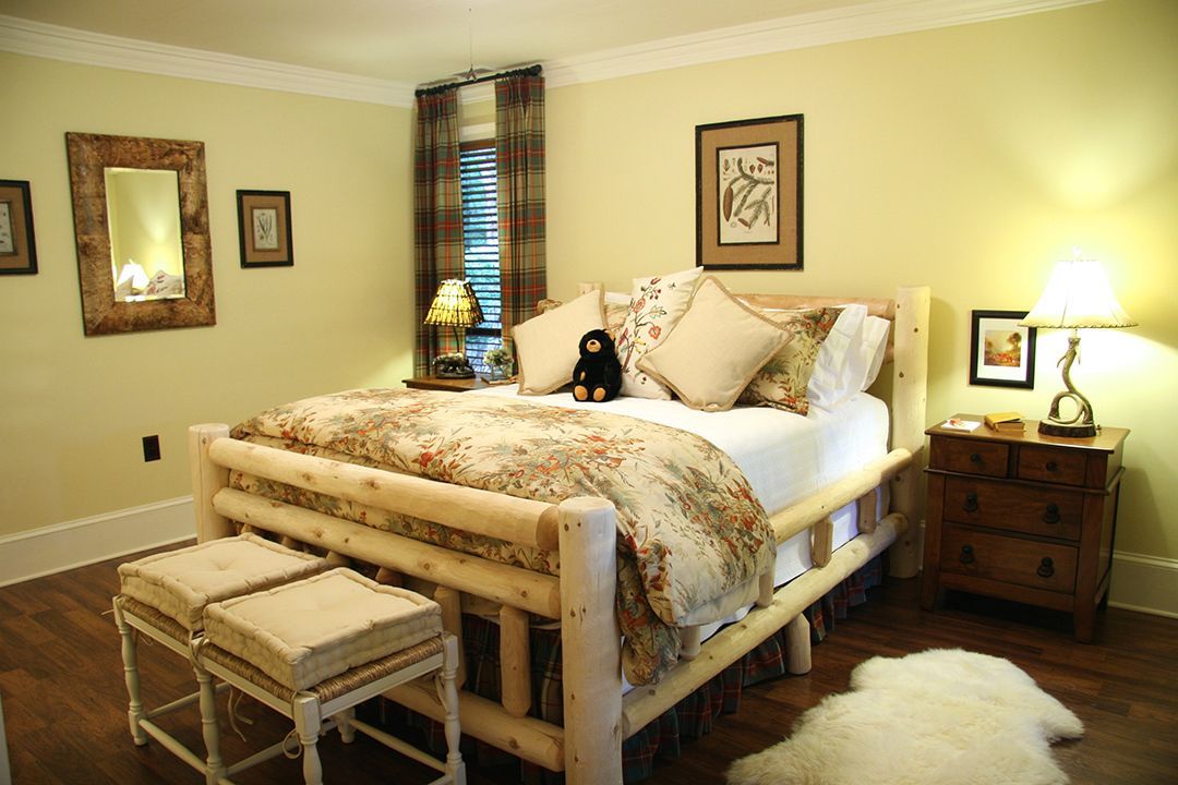 A bedroom with a log bed , dresser , nightstand , and mirror.