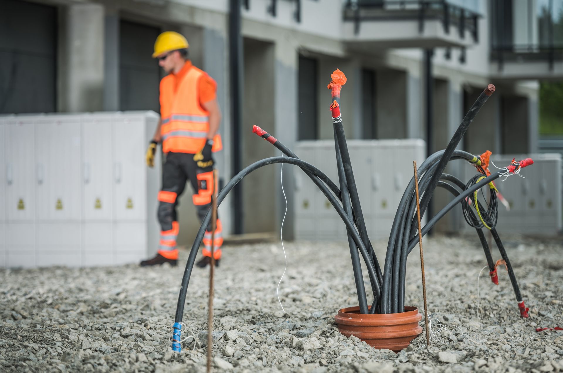 A construction worker is standing next to a bunch of electrical wires on a construction site.