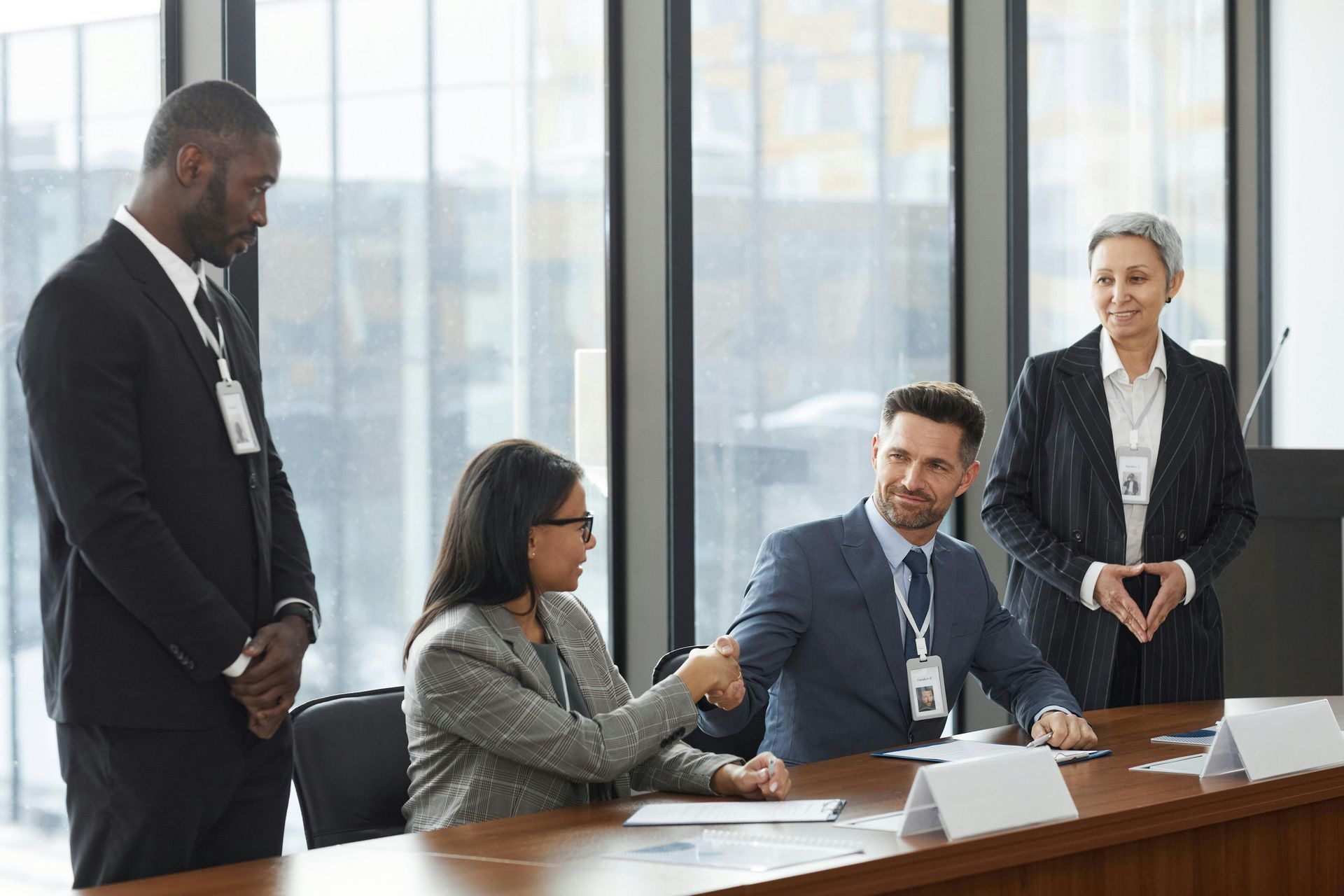 Business meeting in a bright conference room, with four professionals discussing documents around a table.