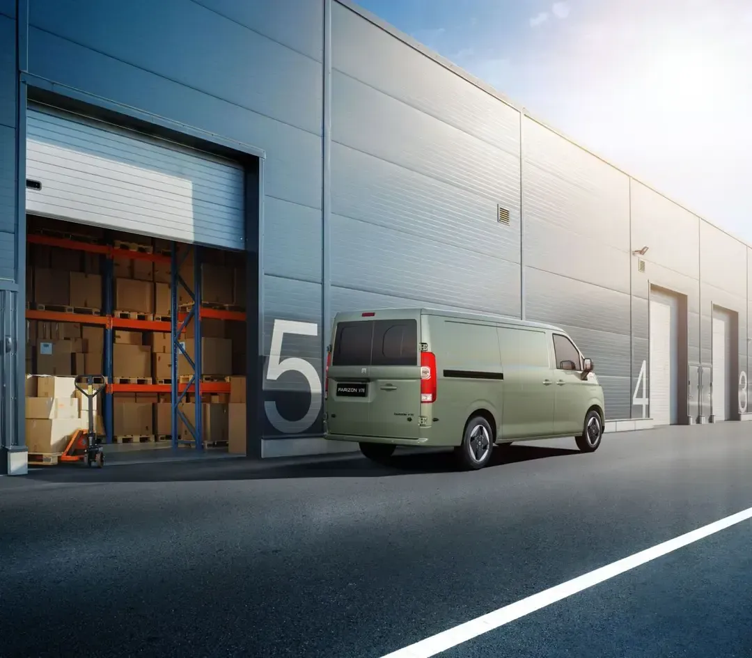 A light-colored cargo van parked in front of a warehouse loading dock marked with the number five.