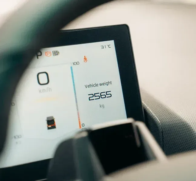 Close-up of a digital vehicle dashboard display showing 0 km/h and a vehicle weight of 2565 kg.