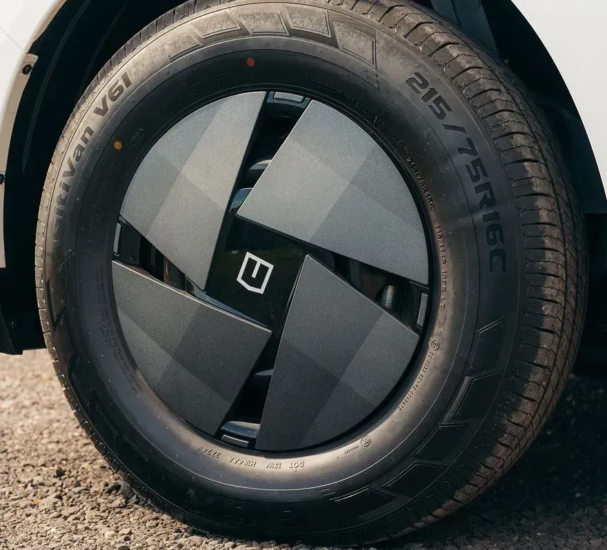 A modern, matte dark gray aerodynamic wheel cover with a geometric design and a central logo, mounted on a vehicle tire.