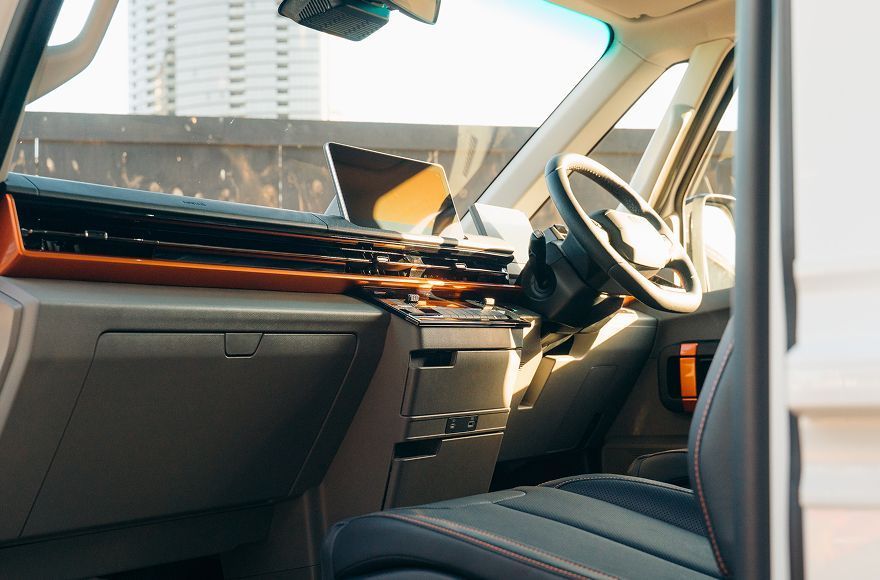 A view of the interior of a vehicle, showing the dashboard, passenger side glovebox, steering wheel, and front seats.