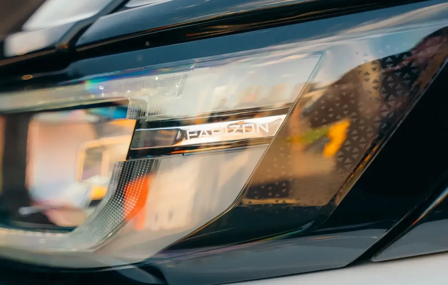 Close-up of a modern car headlight with a translucent, textured housing and a sleek internal trim detail.