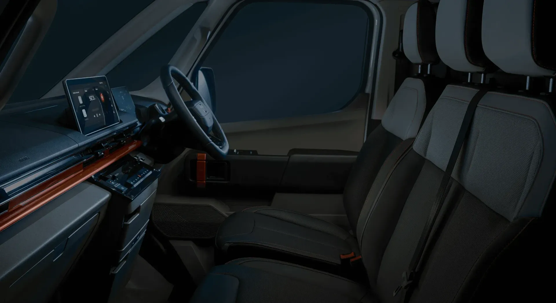 Interior of a vehicle featuring dark fabric seats with gray headrests, a modern dashboard, and a wooden trim accent.