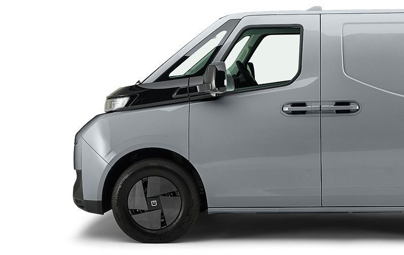 Side profile of a sleek, light grey modern delivery van with a black front bumper and black aerodynamic hubcaps.